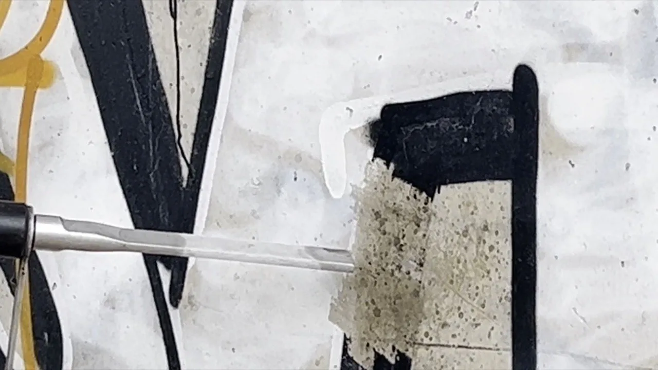Nahaufnahme der Strahld&uuml;se beim Graffiti entfernen, freigelegte Stelle mitten in der Farbschicht auf Beton