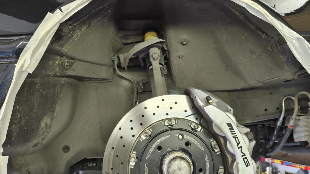 Gereinigter Unterbodenbereich am Mercedes C55 AMG, Radhaus sauber, Bremse und Kanten zur Vorbereitung abgeklebt