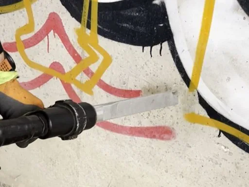 Graffiti entfernen in &Ouml;hringen im Detail: Strahld&uuml;se arbeitet sich durch die Farbschicht auf dem Beton