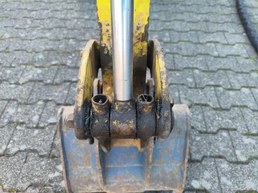 Minibagger-Gelenk mit dick aufgetragenem, verhärtetem Altfett, wie es sich über Jahre am Baggerarm ansammelt