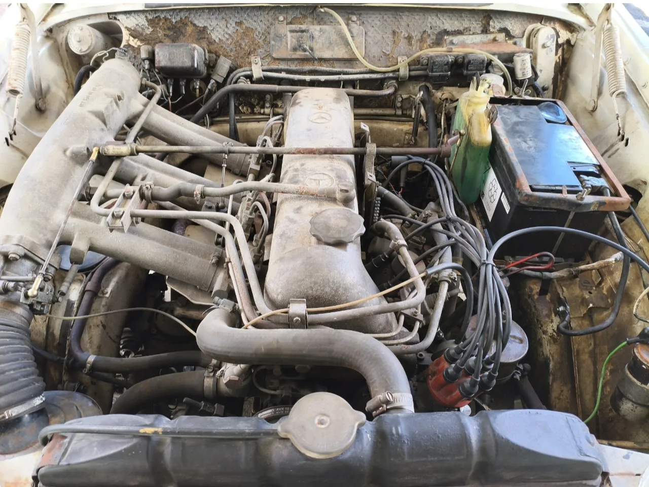 Motorraum reinigen am Oldtimer, vorher: Sechszylinder eines Mercedes-Klassikers mit Staubschicht auf Ventildeckel und Leitungen, Rost an der Stirnwand
