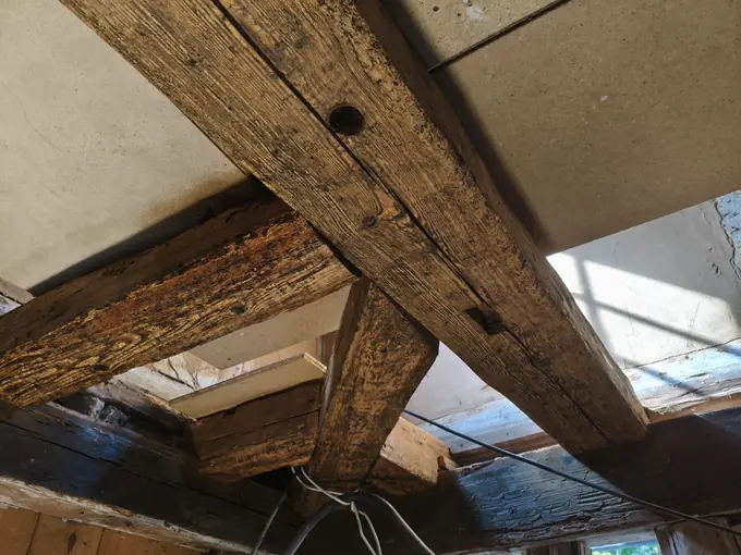 Gestrahlte Deckenbalken mit Holznägeln, darunter noch dunkel gestrichene Balken