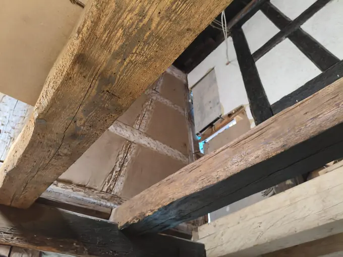 Balken nach dem Trockeneisstrahlen auf Holz: Oberseite freigelegt, Seitenfläche noch mit schwarzer Farbe