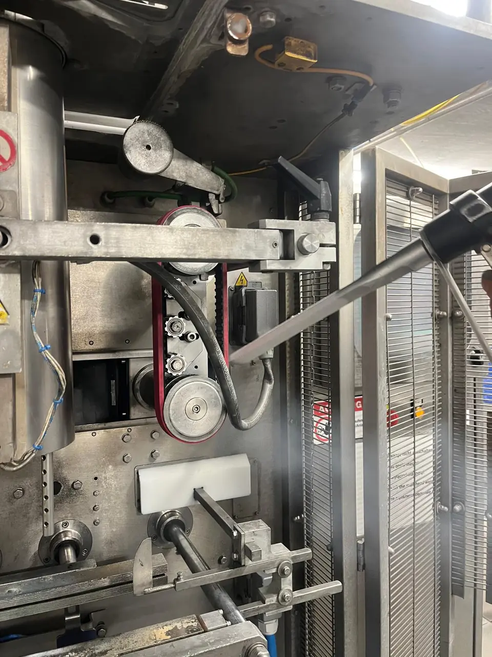 Industriereinigung in der Lebensmittelindustrie: Trockeneisstrahlen am Riementrieb einer Produktionsmaschine, der Strahl löst die Ablagerungen