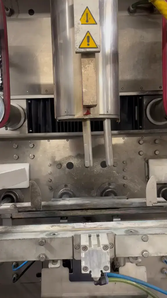 Bereich unter dem Formrohr einer Produktionsmaschine vor der Reinigung, die Platte ist von Ablagerungen überzogen